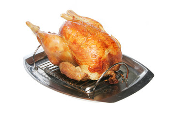 Roasted chicken on a carving dish on white
