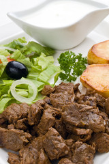 Grilled meat with baked potatoes, sauce and vegetable salad