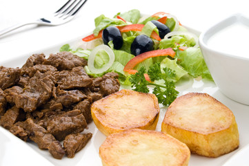 Grilled meat with baked potatoes, sauce and vegetable salad