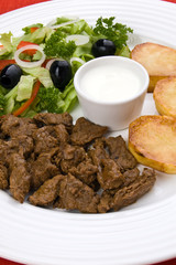 Grilled meat with baked potatoes, sauce and vegetable salad