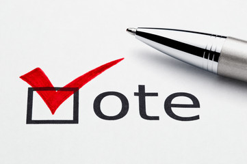 Red checkmark on vote checkbox, pen lying on ballot paper.