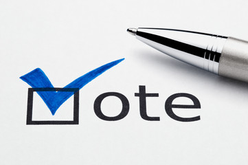 Blue checkmark on vote checkbox, pen lying on ballot paper.