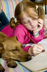 Schoolgirl is making homework together with her dog