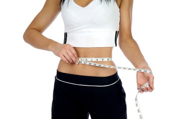 Young woman measuring her waist with a tape measure