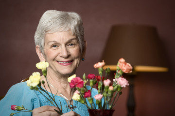 Senior woman at home with colorful flowers