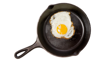 A fried egg in a black iron skillet on a white background