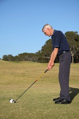 Senior golfer lining up his tee shot