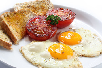 Ontbijt van gebakken eieren en tomaten, met volkoren toast.