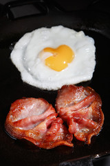 frying egg and bacon rashers on a pan, shallow DOF
