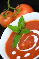 Tomato soup with basil leafs and sour cream as decoration