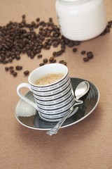 Cup of cappuccino with cinnamon and spilled out coffee beans.