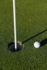 A white golf ball near the hole of a golfing green or course