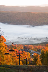 Chairlift at fall mountains with morning mist in the valley