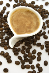 Cup of creamy espresso coffee and beans on white background