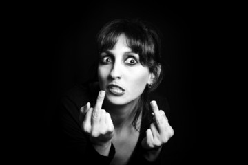 Fototapeta premium Black and white portrait of the young woman making rude gesture
