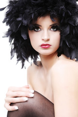 Topless young woman in black feathers on white background.