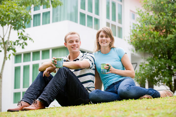 A young couple sitting outside in garden in front of the house