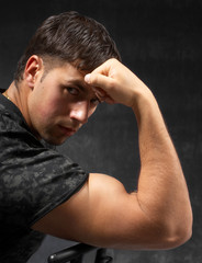 strong man showing his bicep against dark background