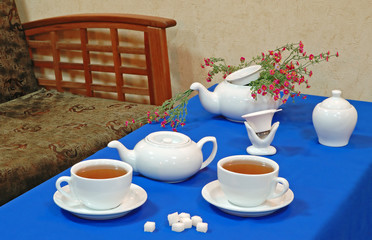 Cups of English tea with tea service and pink wild flowers