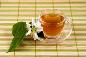 Transparent teacup with tea and flower