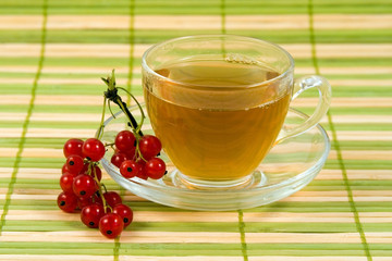 Transparent teacup with tea and red currant