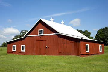 Fototapeta na wymiar A freshly painted red barn on a green meadow