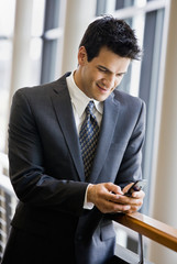 Businessman text messaging on cell phone in office lobby