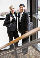 Female co-workers posing together in corner of office building