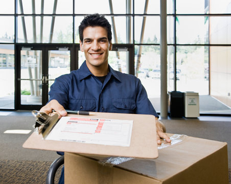 Delivery man in uniform with stack of cardboard boxes