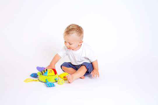 One year old baby boy enjoys playing with toys. Studio Shot.