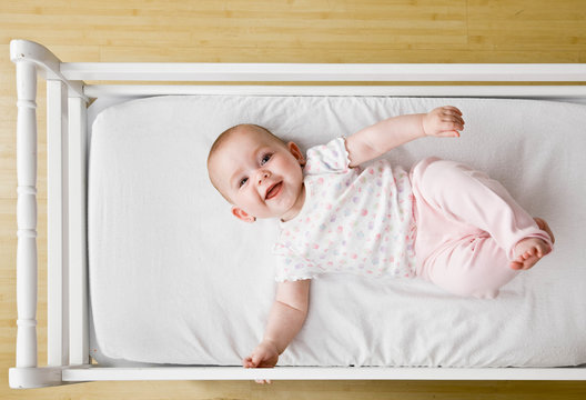 Happy, playful baby laying in crib