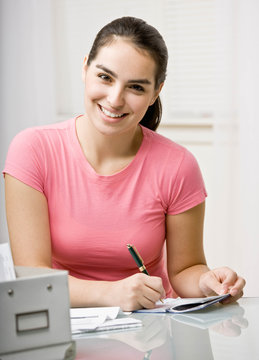 Woman writing checks in checkbook to pay monthly bills