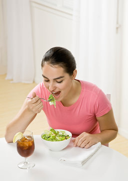 Happy woman eating wholesome, fresh bowl of salad