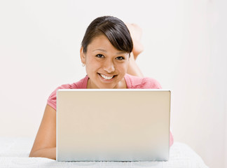 Relaxed woman laying on bed and typing on laptop