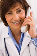 Senior female doctor calling on phone, smiling.