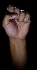 Vertical image of a fist in low key lighting with a rim-light.