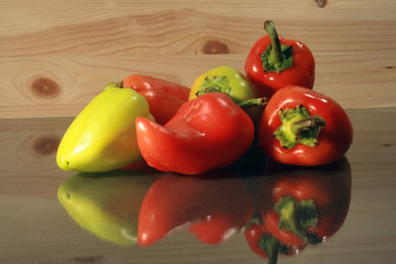 Red and green sweet peppers lying on glassy table