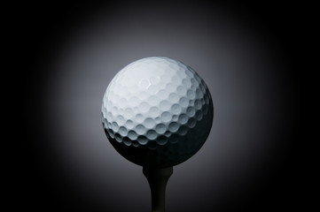 Golf ball on tee on black