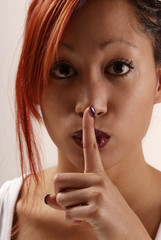 Naklejka premium junge Frau halten Zeigefinger an Mund deuten leise