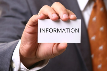 Business man holding card with text INFORMATION