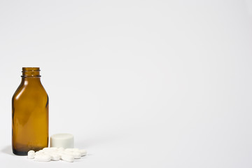 A brown bottle, opened with pills around the base