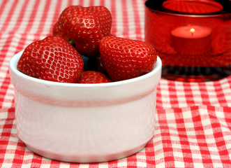 Strawberries in crock with lit candle