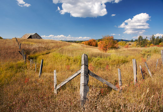 Beautiful Fall Landscape with Rustic Barn, Fence and Clouds