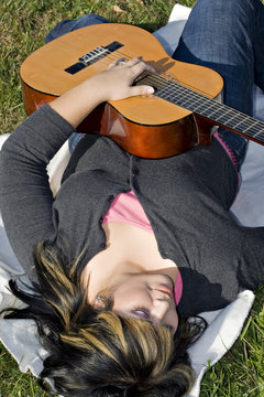 A Young Hispanic Woman Playing A Guitar Outside