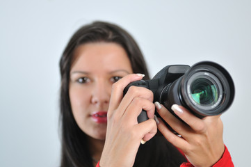 Young woman holding camera in hand taking picture isolated