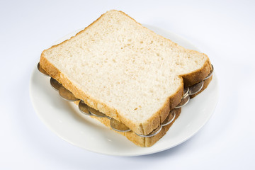A sandwich filled with coins on a white plate