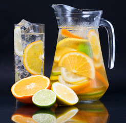 Citrus ice water glass and carafe over dark background