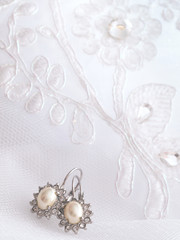 Wedding details. silver ear-rings lying on embroidered veil