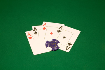 Four aces on the green table in casino with chips