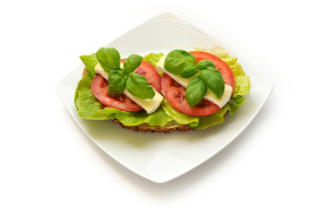Sandwich of lettuce, tomato, camembert and fresh basil.